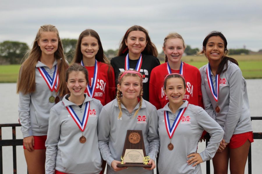Girls cross country team poses with their district trophy.