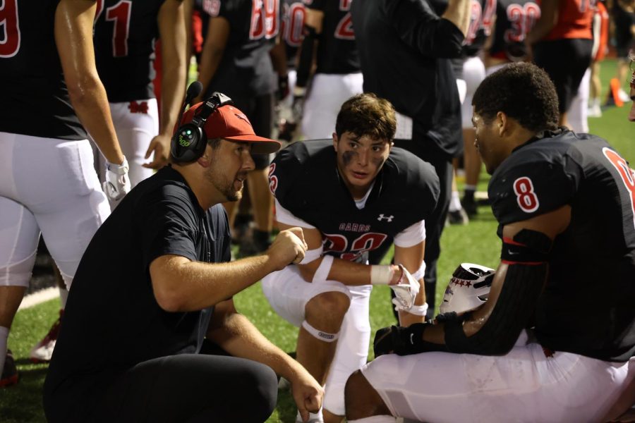 Coach Spann gives some tips to seniors Josh Nicholas (23) and Jacob Fields (8) during the China Spring game on Sept. 2. The Cardinals played a close game against the defending 4A Division II state champs and lost 42-41 in the last minute.
