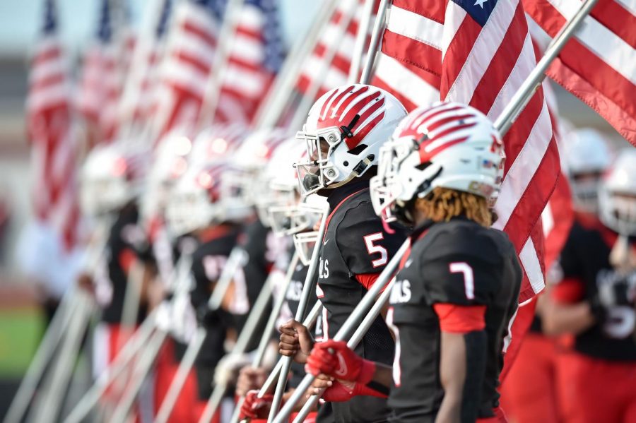 Varsity football players carry American flags onto the field before the game in honor of Patriot Day, Sept. 11.