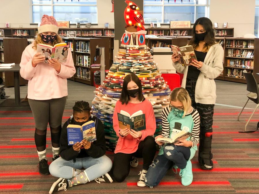 Reading Around the Book Tree. Several students gather in the library around the creative Cardinal book tree to enjoy their texts.