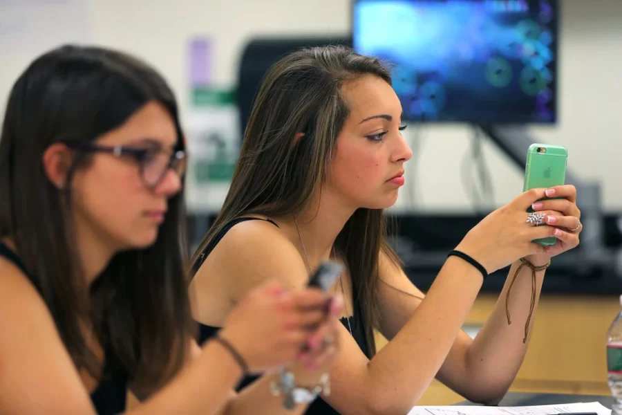 Melrose High students Beatrice Affatato (left) and Miranda Lombardo use smartphones in Blair Cochran’s physics class.