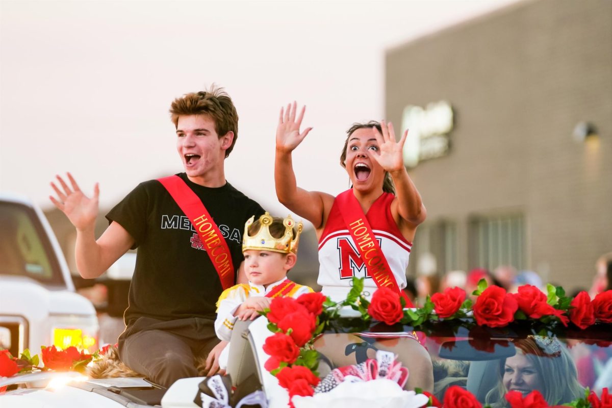 Seniors Kolby Schulz and JoJo Miller, two of the homecoming court nominees, wave to the crowd during the annual parade on Oct. 18.