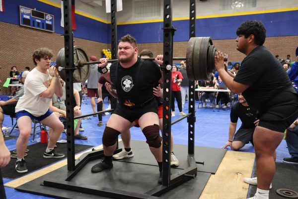 Junior Owen Hollenbeck squats 700 lbs at the Community High School powerlifting meet on Feb. 16. Hollenbeck won first place in his weight class lifting a total of 1,685 lbs.